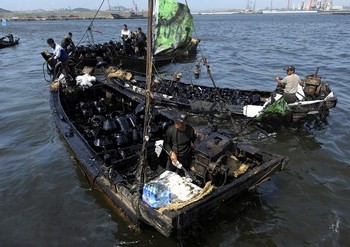 Местные жители вылавливают нефть из Жёлтого моря. Фото: LIU JIN/AFP/Getty Images