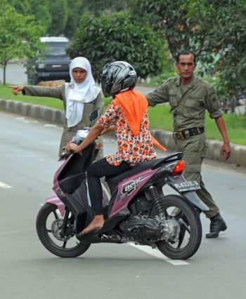 Поліція затримує жінку-мотоцикліста в обтислому одязі на контрольно-пропускному пункті в Банд-Ачех, Індонезія, 2 грудня 2009. Фото: Romeo Gacad/AFP/Getty Images