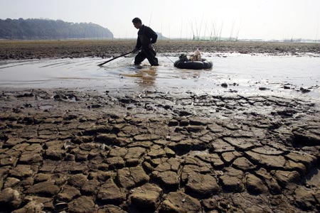 Працівник служби захисту навколишнього середовища стоїть по коліна в каламутній воді. Фото: Photo by China Photos/Getty Images
