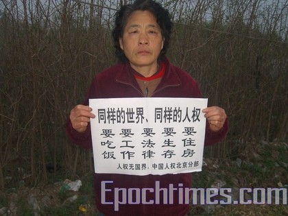 Апеллянтка держит лист с надписью: «Единый мир, единые права человека. Мы хотим есть, нам нужна работа, законы, условия для существования, жильё». Фото: The Epoch Times