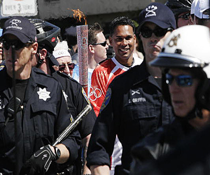 Спортсмен бежит с олимпийским факелом в плотном оцеплении полиции в Сан-Франциско 9 апреля 2008 г. Фото: Ryan Anson/AFP/Getty Images