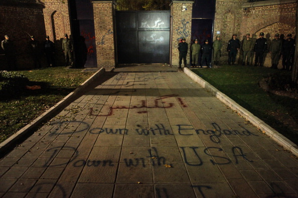 Иранские полицейские стоят на страже за лозунгами, написанными на земле демонстрантами, где проживали британские дипломаты и члены их семей. Великобритания закрыла свое посольство в Тегеране 30 ноября. Фото: Rauf Mohseni/Getty Images