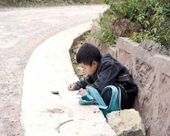 Деревенский мальчик выполняет домашнее задание – прямо на дороге. Фото с сайта secretchina.com