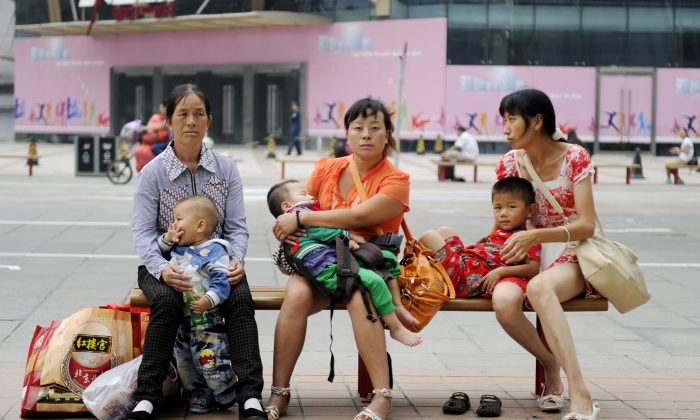 Жінки з дітьми сидять на лавці на одній з вулиць Пекіна, 6 вересня 2012 року. Wang Zhao/AFP/Getty Images