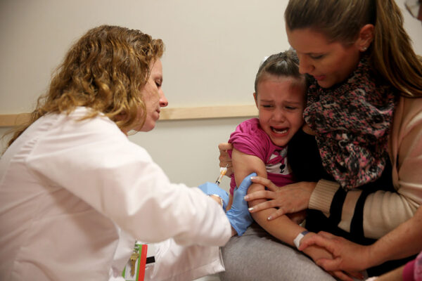 Педіатр дитячої лікарні Маямі доктор Аманда Порро робить щеплення від кору 4-річній Софі Баркин, поки її мати Габріель Баркин тримає її на руках, Маямі, штат Флорида, 28 січня 2015 року. (Joe Raedle/Getty Images)