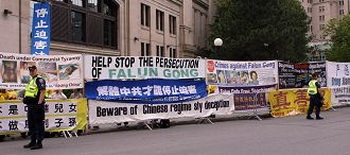 Надписи на плакатах: 'Прекратите преследование Фалуньгун» и «Привлечь Цзяня, Ло, Лю и Чжоу к правосудию'. Фото с minghui.org