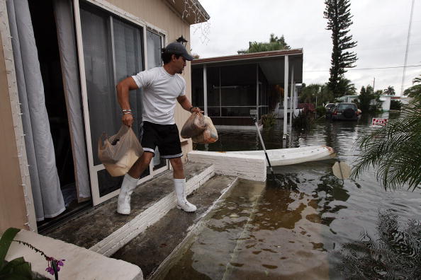 Мужчина выносит вещи из своего затопленного дома. Сильный шторм принес в южную Флориду около 35 см осадков, которые вызвали наводнение. Фото: Joe Raedle/Getty Images