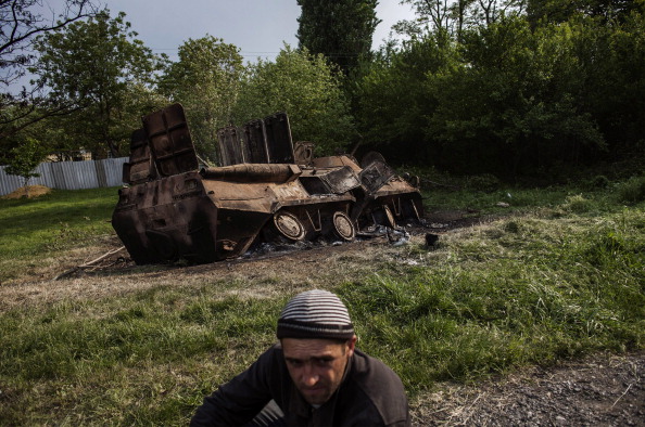 Пророссийский активист сидит рядом с уничтоженным БТР-ом украинской армии возле с.Октябрьское (в 20 км от Краматорска) 14 мая 2014 года, где накануне под обстрелом боевиков погибли 7 украинских солдат. Фото: FABIO BUCCIARELLI/AFPA/Getty Images