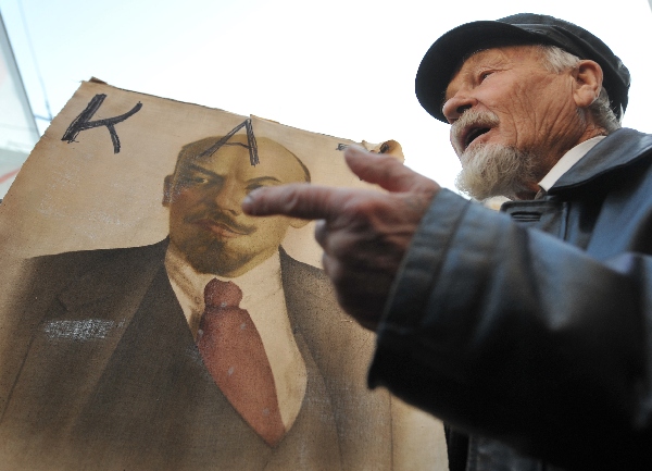 Мужчина парадирует Ленина возле его портрета на акции украинских коммунистов во время открытия отреставрированного памятника Ленину. Киев, 27 ноября 2009 год. Фото: SERGEI SUPINSKY/AFP/Getty Images