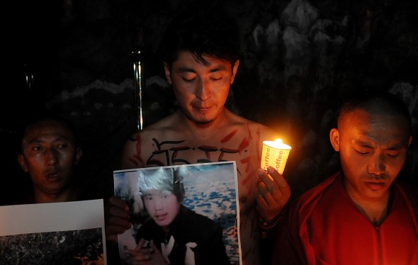 Находящийся в изгнании тибетец во время акции со свечами держит фотографию 27-летнего Сангая Гьяцо, погибшего в результате самосожжения. В минувшие выходные в провинции Ганьсу поджёг себя ещё один житель Тибета. Фото: STR/AFP/GettyImages