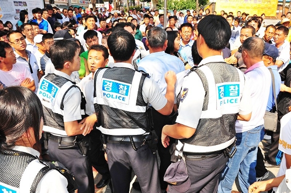 Обвиняемый Цуй пытается напасть на сотрудников правопорядка. Фото: Guohuan Jin/The Epoch Times