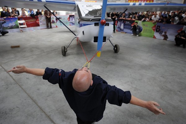 Дон Чжаншень тащит самолёт, привязанный к его векам. Фото с epochtimes.com