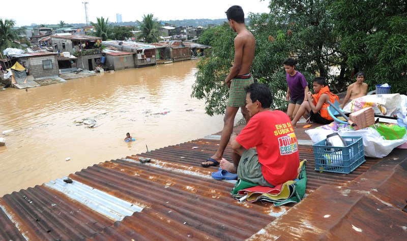 Люди спасаются от стихии на крышах домов в окрестностях Манилы, Филиппины, 9 августа 2012 года. Фото: JAY DIRECTO/AFP/GettyImages