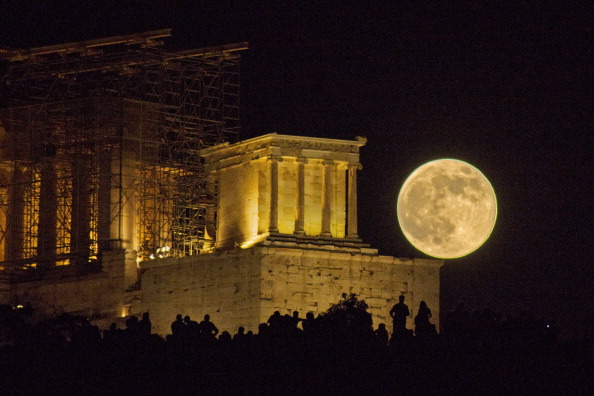 Суперлуна восходит над афинским Акрополем. Фото: Nikolaos Pantazis / Getty Images