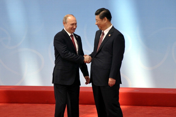 Президент России Владимир Путин приветствует генсека КНР Си Цзиньпина на церемонии открытия в Шанхае саммита по взаимодействию и мерам доверия в Азии 21 мая 2014 года. Фото: Ali Ihsan Cam/Anadolu Agency/Getty Images