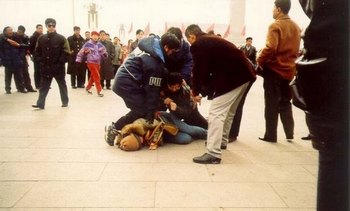 Несколько китайских полицейских в штатском прямо на улице скрутили женщину-последовательницу Фалуньгун. Фото с epochtimes.com