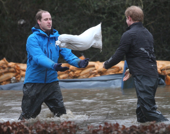 Принц Уильям, герцог Кембриджский (слева) ловит мешок с песком от брата, принца Гарри, во время наводнения в городе Дэтчет, Англии, 14 февраля 2014 года. Фото: Peter Macdiarmid/Getty Images