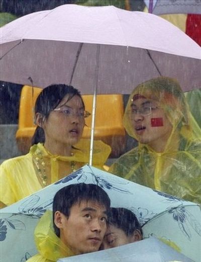 Зрители под проливном дожди ждут результатов по соревнованиим по стрельбе из лука среди женщин 10 августа 2008 г. в Пекине. Фото: AFP
