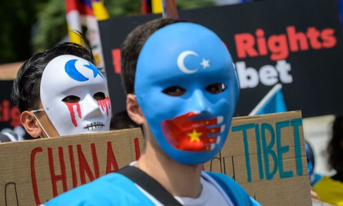 Уйгурские активисты в масках во время акции протеста против зимних Олимпийских игр 2022 года в Пекине перед Олимпийским музеем в Лозанне 23 июня 2021 года, когда в акции приняли участие около 200 человек. (Fabrice COFFRINI/AFP)