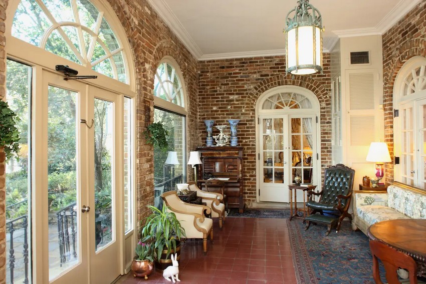 Фрамуги над французской дверью позволяют свету проникать в солнечную комнату дома, из которой открывается вид на реку Фаул. Цегла сочетается с красной плиткой на полу. Комната служит более непринужденным переходным пространством между садами и официальной столовой. (Bellingrath Gardens & Home)