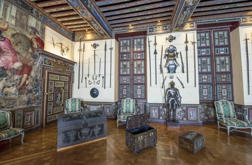 Зброярня містить багато оригінальних меблів і також є найбільшою кімнатою в замку. Безцінні гобелени та меблі прикрашають кімнату, а також зброя та обладунки. Стеля має розписані балки та дерев'яні панелі з квітковими мотивами та латинськими написами. У кімнаті представлений гобелен XVII століття, комод часів Людовика XIV та дерев'яний різьблений димар французького художника Жана Моньє. (Yuri Turkov/Shutterstock)