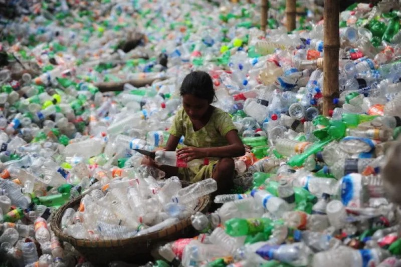 Дитина з Бангладеш сортує поліетилентерефталатні (ПЕТ) пляшки, призначені для переробки, в несприятливих умовах праці в Дацці, 21 серпня 2013 року. (UNIR UZ ZAMAN/AFP via Getty Images)