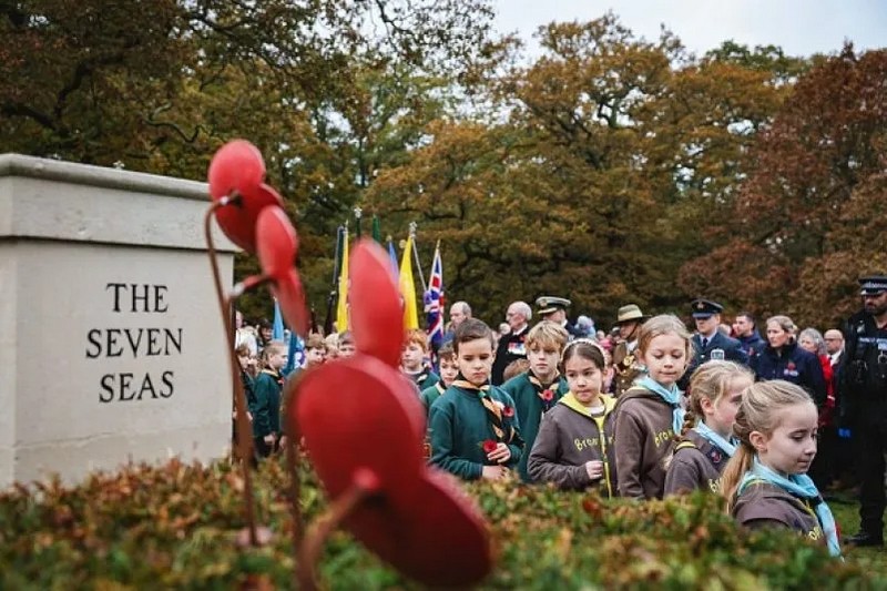 Діти, які представляють відділення скаутської та гідської організацій, проходять повз меморіал полеглим з маками в Хартлі Вінтні, на захід від Лондона, під час церемонії поминання 12 листопада 2023 року. (ADRIAN DENNIS/AFP via Getty Images)