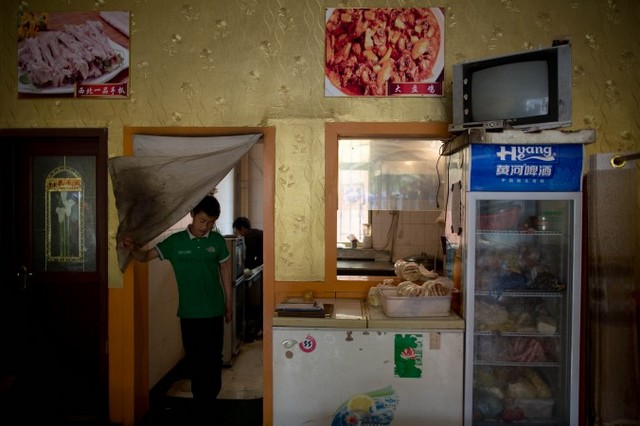 Официант выходит из кухни ресторана в городском округе Цзяюйгуань северо-западной провинции Китая. Фото: Ed Jones/AFP/Getty Images
