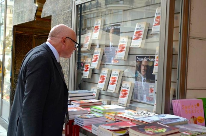 Писатель, аналитик по Китаю и исследователь в сфере прав человека Итэн Гутманн смотрит на свою новую книгу «Бойня» в оконной витрине книжного магазина Frick в Вене, где он недавно проводил публичное чтение