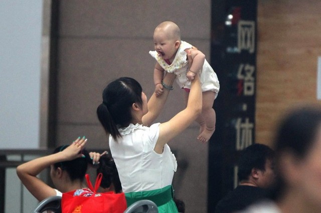 Жінка тримає дитину в Чженчжоу провінції Хенань, що в центральному Китаї, 29 липня 2014 р. У недавніх репортажах у державних ЗМІ Китаю повідомлялося про надприбутки, експлуатацію сурогатних матерів та аборти, пов'язані з вибором статі дитини, що притаманні бізнесові сурогатного материнства