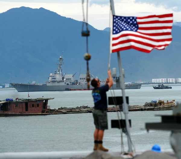 Моряк поднимает флаг США на корабле USNS Safeguard