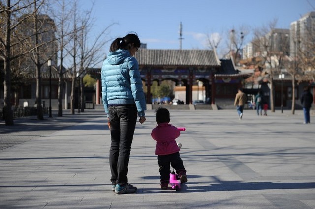 Женщина с ребёнком гуляет в парке Пекина. Китайские власти в области планирования семьи в последнее время отменили компенсацию родителям, потерявшим своих единственных детей. 