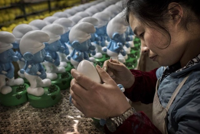 Робітниця на заводі в Дехуа китайської провінції Фуцзянь розфарбовує керамічних &laquo;Смурфів&raquo; на експорт, 4 грудня 2014 року