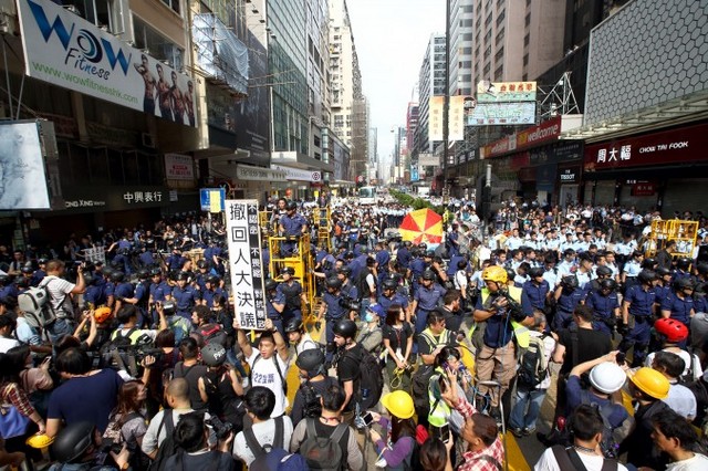 Під час зачистки поліцією місця акції протесту у Монг Кок демонстрант у білій футболці тримає транспарант, на якому викладено вимогу, аби влада відкликала рішення ВЗНП, що обмежує загальне виборче право у Гонконзі, 26 листопада 2014 року