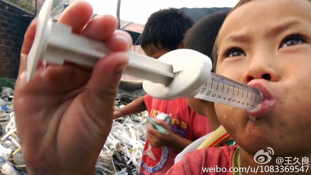 Ребёнок играет с пластиковым шприцем возле груды пластиковых отходов в неустановленном месте в Китае, август 2013 года