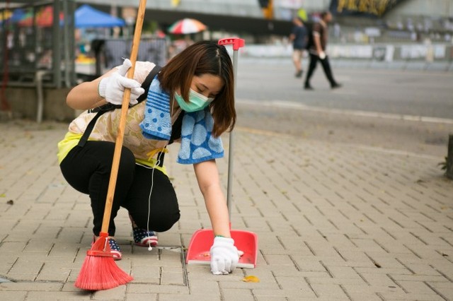 Демонстрантка-волонтёр тщательно очищает пространство между кирпичами неподалёку от дороги в Центральном районе Гонконга, которую заняли протестующие в поддержку демократии, 9 октября 2014 года. По словам женщины, её никто не просил этого делать. Она просто подумала, что кому-то следует убрать, и некоторые протестующие добровольно это делают