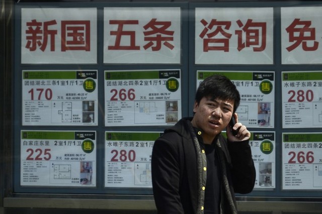 Китаєць розмовляє по мобільному телефону біля будівлі агентства нерухомості в Пекіні, 15 квітня 2013 р. Нещодавно оприлюднений «Індекс страждань покупця житла» показав, наскільки важко придбати житло в Китаї