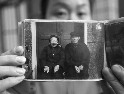 Внучка держит фотографию 1980-х годов бабушки с дедушкой. Скриншот: Wuhan Evening Times