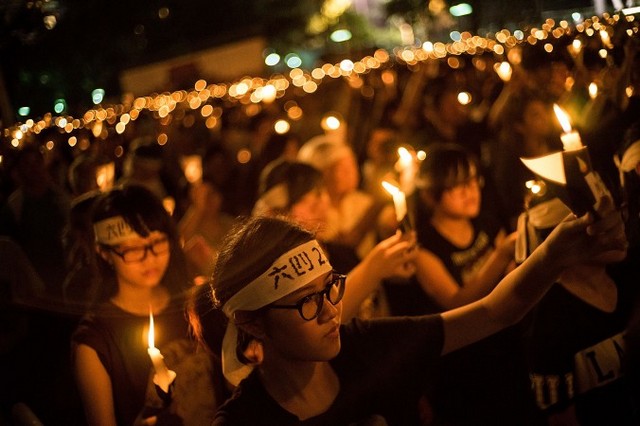 Люди, незважаючи на рясний дощ, беруть участь у всеношній із запаленими свічками на 25-ту річницю протестів на площі Тяньаньмень. 4 червня 2014 року в Гонконзі