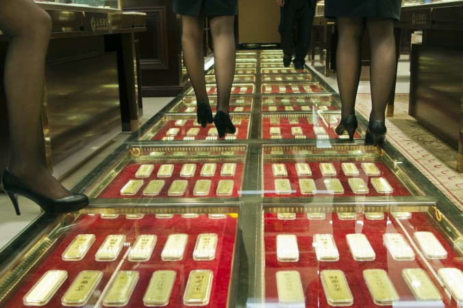 Китайские продавцы ходят по дорожке, вымощенной золотыми слитками, которые оцениваются на сумму, превышающую 100 млн юаней ($16 млн). Магазин золота в Куньмине, КНР, 11 декабря 2012 г. Китай импортирует много золота, но остальной мир не знает, сколько этого драгоценного металла в стране. Фото: STR/AFP/Getty Images