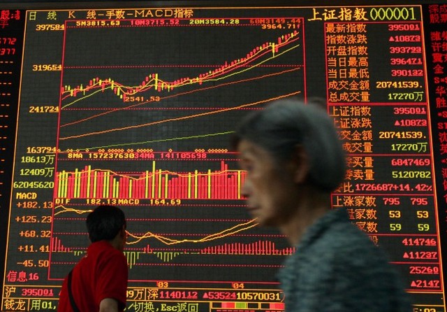 Инвестор проходит мимо фондового индекса в компании, занимающейся ценными бумагами, в китайском городе Ухане